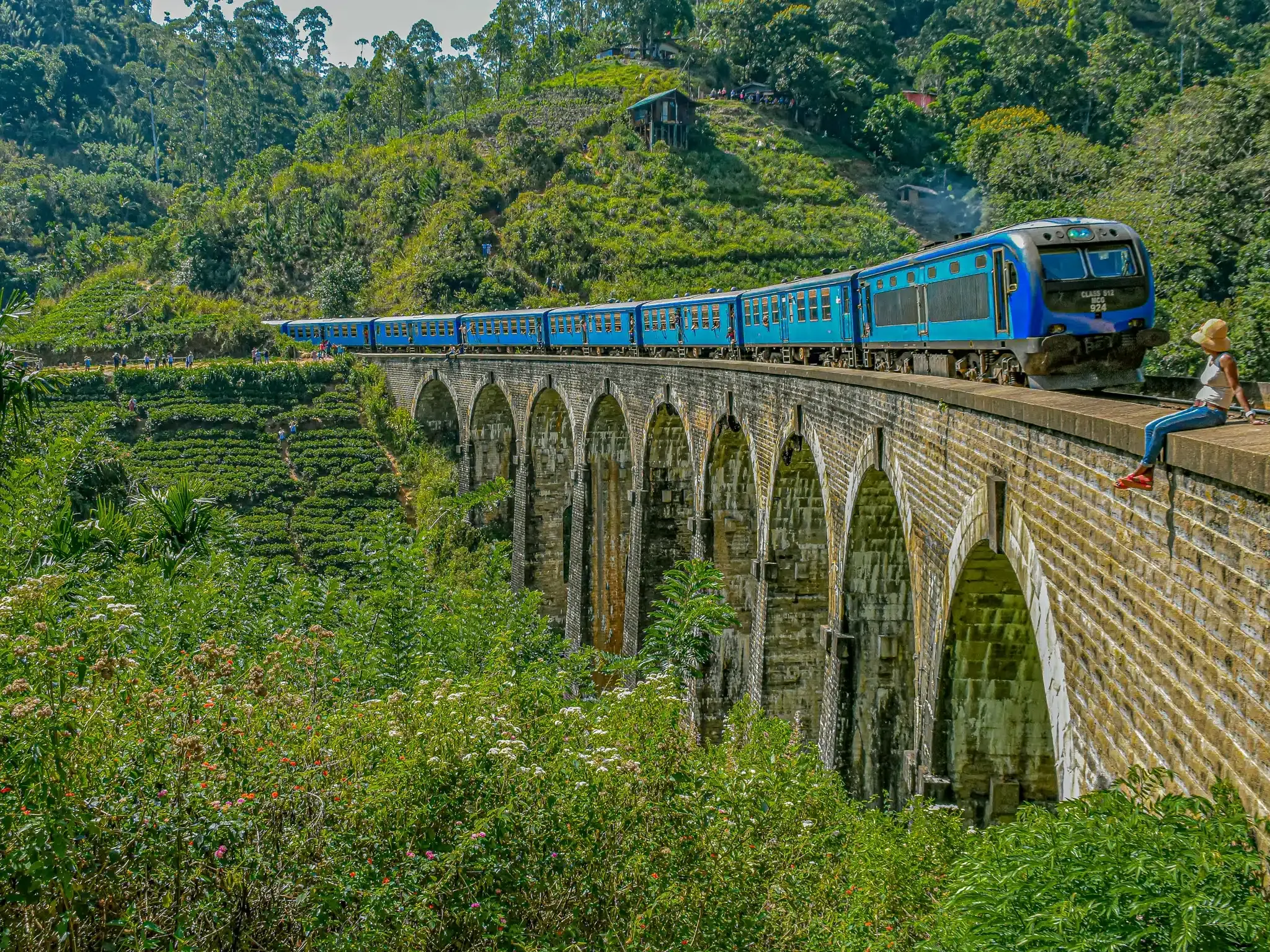 Nine Arch Bridge Ella Sri Lanka with blue train passing through - Iconic colonial railway bridge surrounded by lush tea plantations and misty mountains